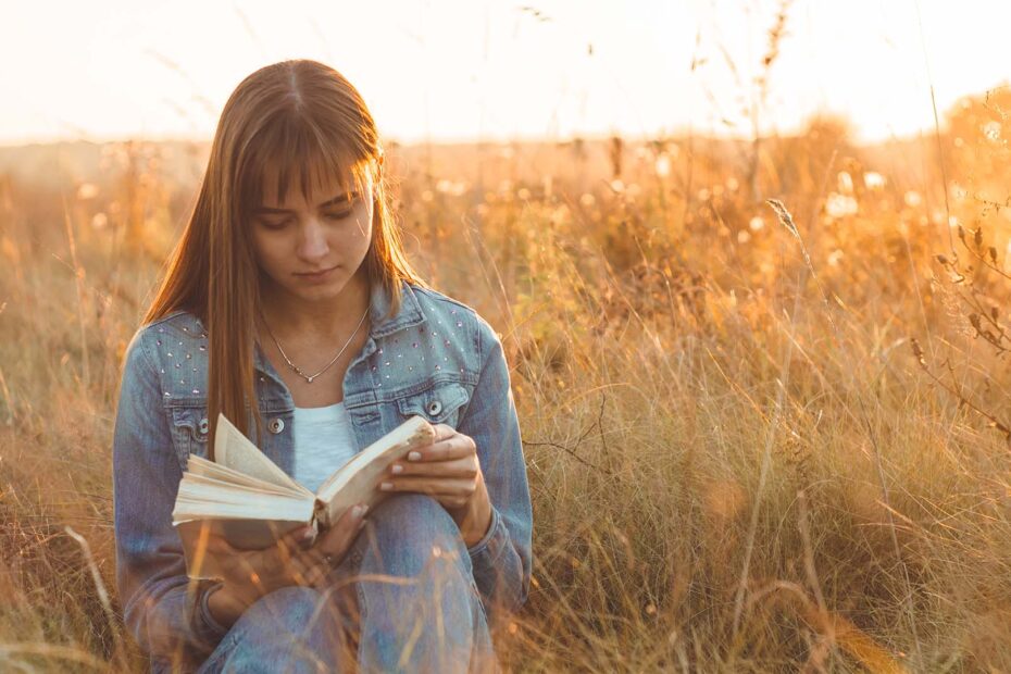 Jonge vrouw die buiten een boek leest